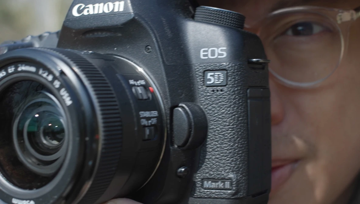 Canon EOS 5D Mark II DSLR camera held up to a person's face during a portrait session.