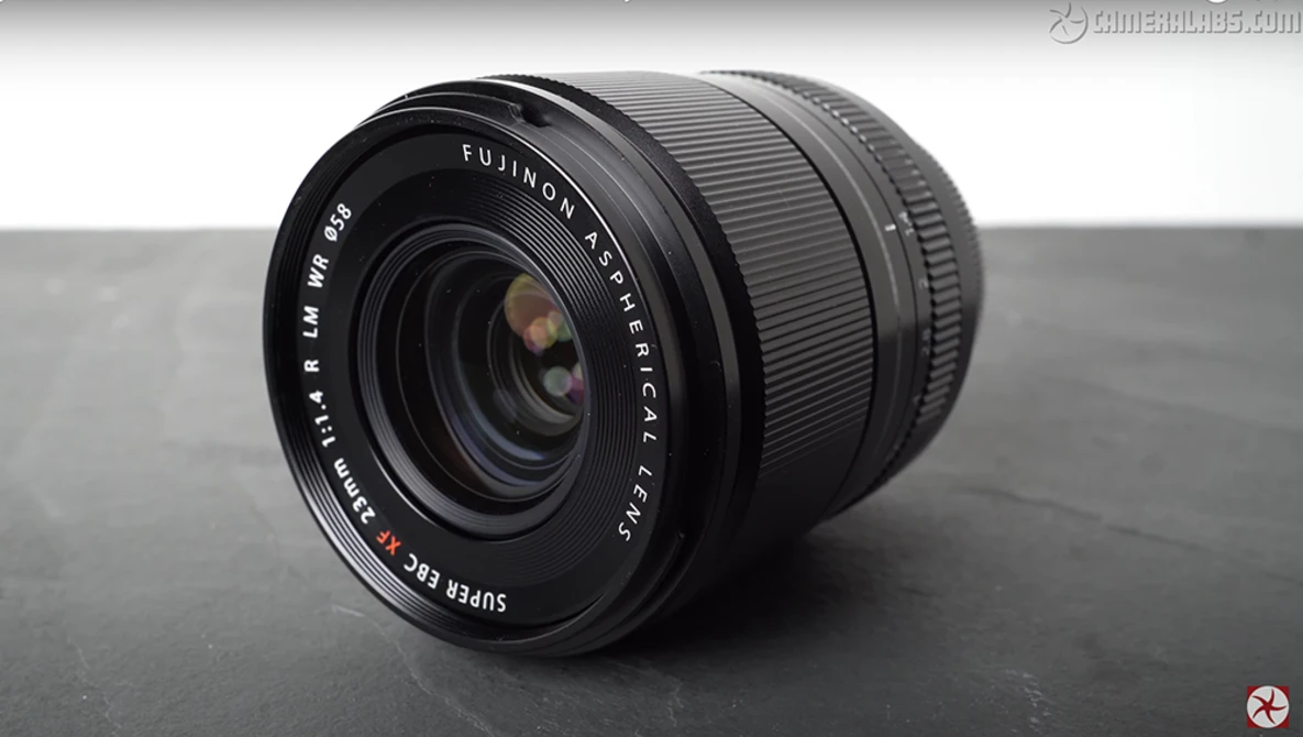 Fujinon XF 18mm f/2 R lens positioned on a gray surface against a neutral background.