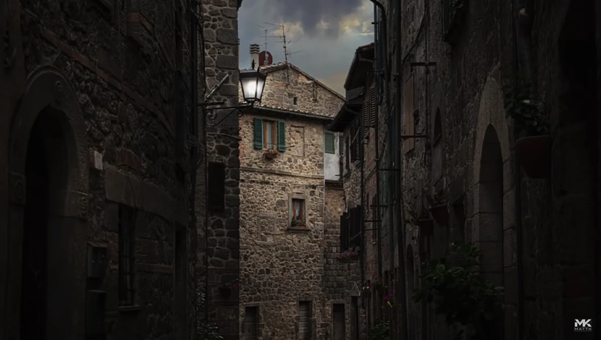 Narrow European stone alleyway with ancient buildings and distant sky visible at the end.