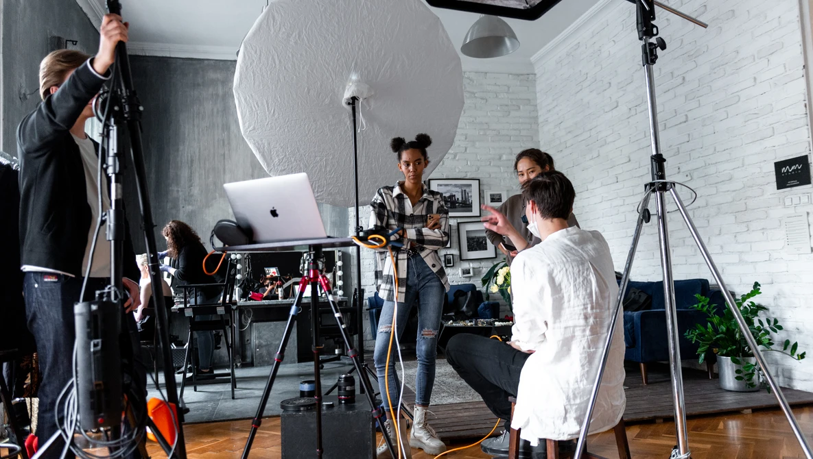 Photography studio setup with crew adjusting lighting equipment and reflectors during a shoot.