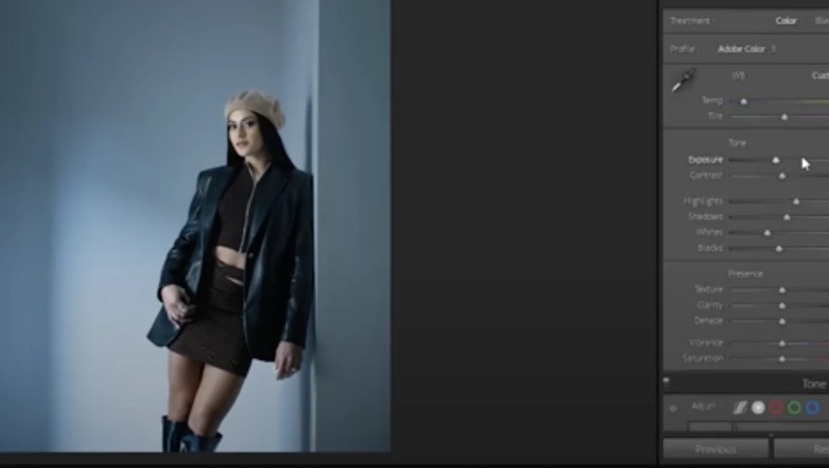 Woman in black blazer and shorts posed against blue studio backdrop with editing software visible.