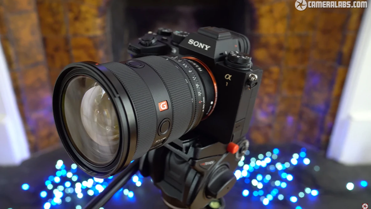 Sony Alpha mirrorless camera with telephoto zoom lens mounted on tripod head, surrounded by blue bokeh lights.