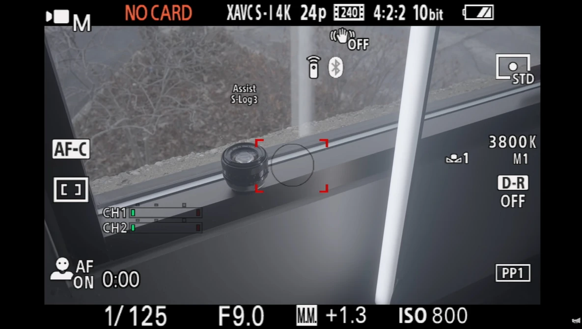 Camera LCD screen displaying manual focus assist with focus peaking overlay on a window scene.