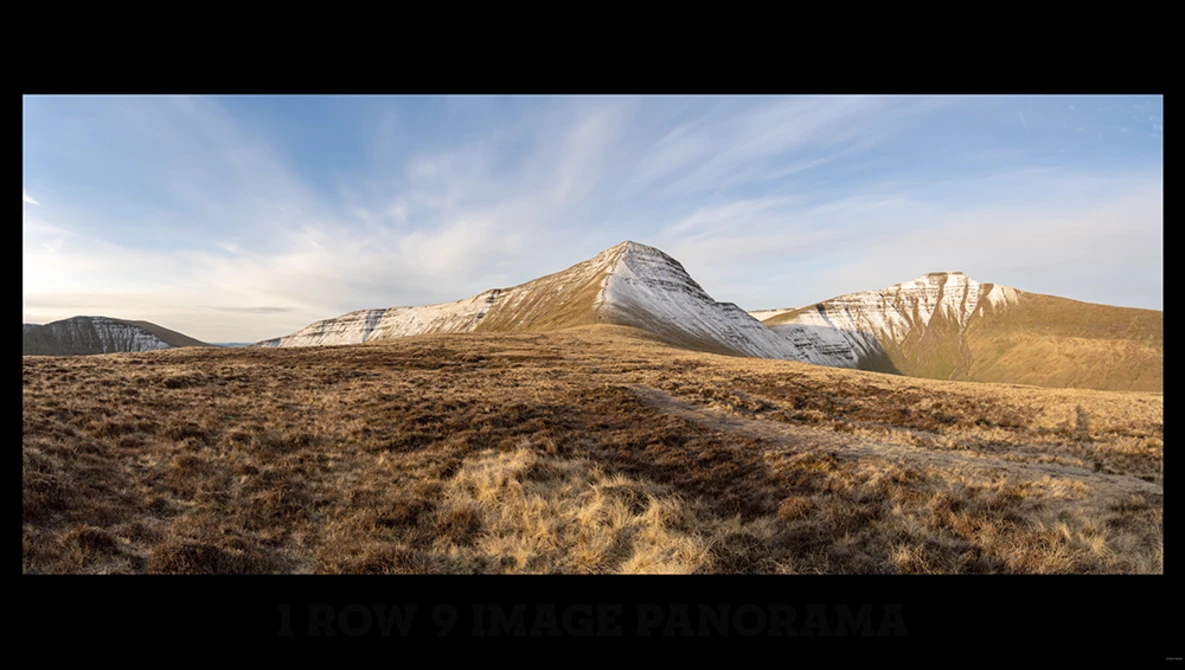 Snow-capped mountain peak rising above arid, sparsely vegetated desert landscape under partly cloudy sky.