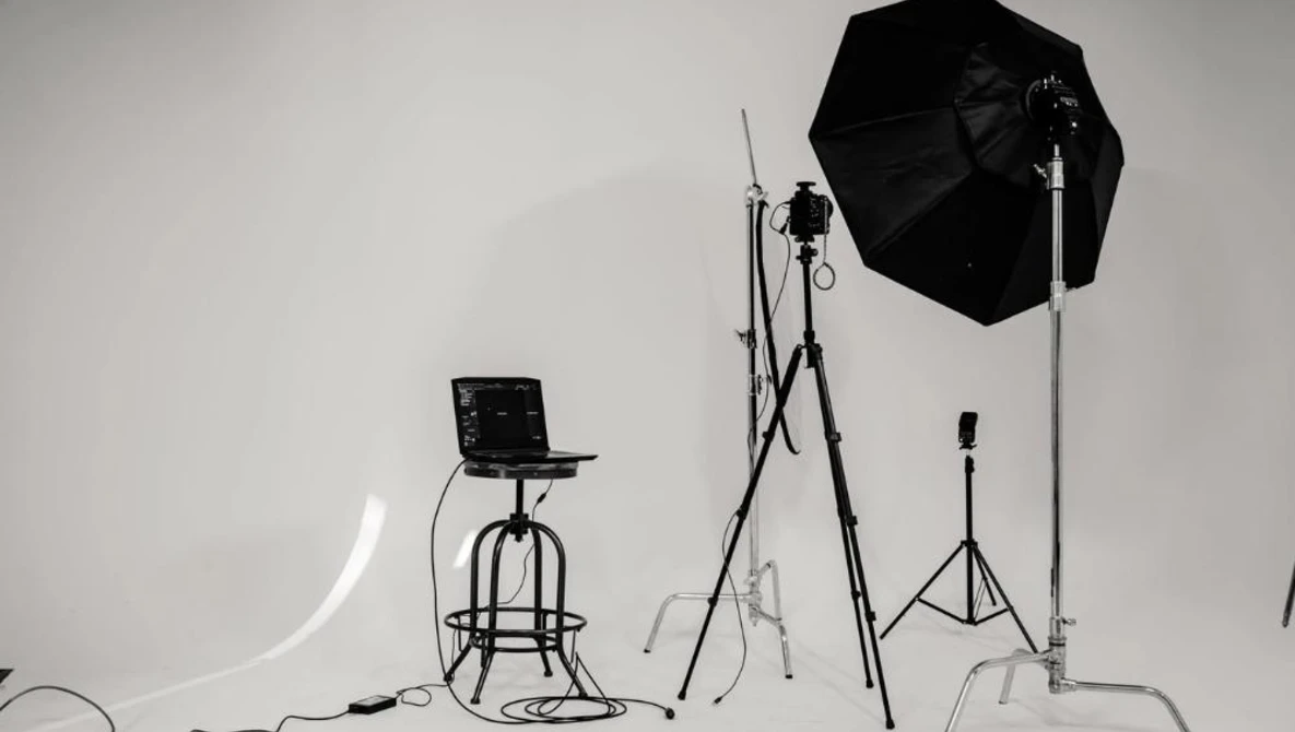 Professional studio lighting setup with softbox, light stands, and reflector on white backdrop.