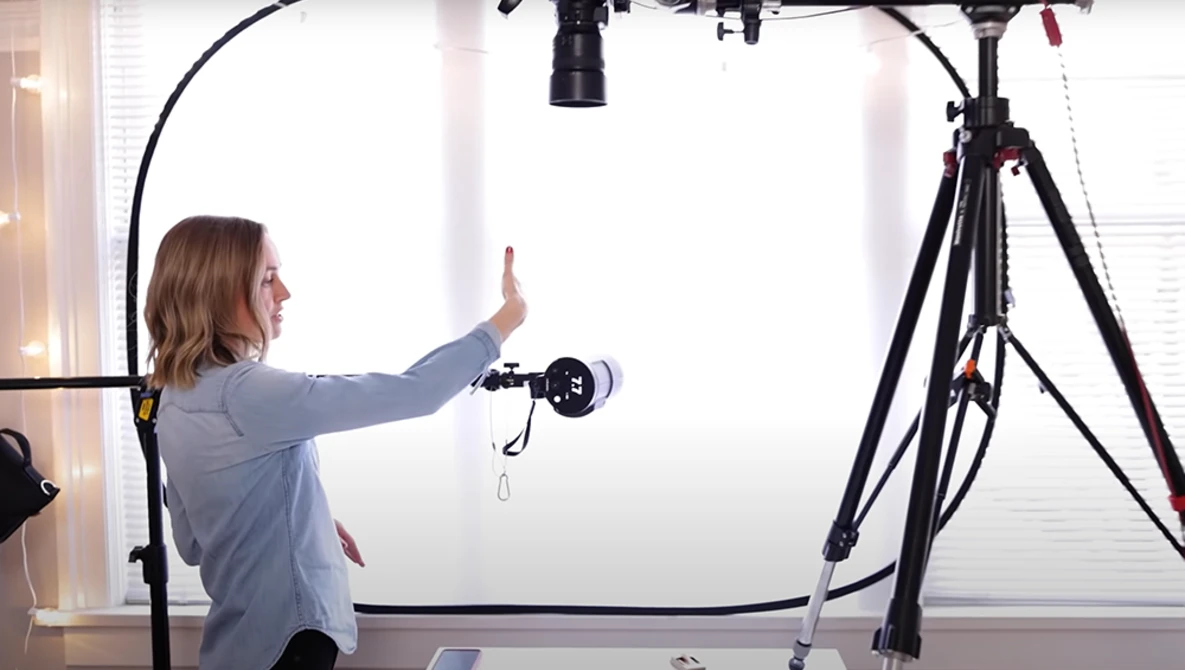Photographer adjusting a ring light mounted on a tripod during a studio setup.