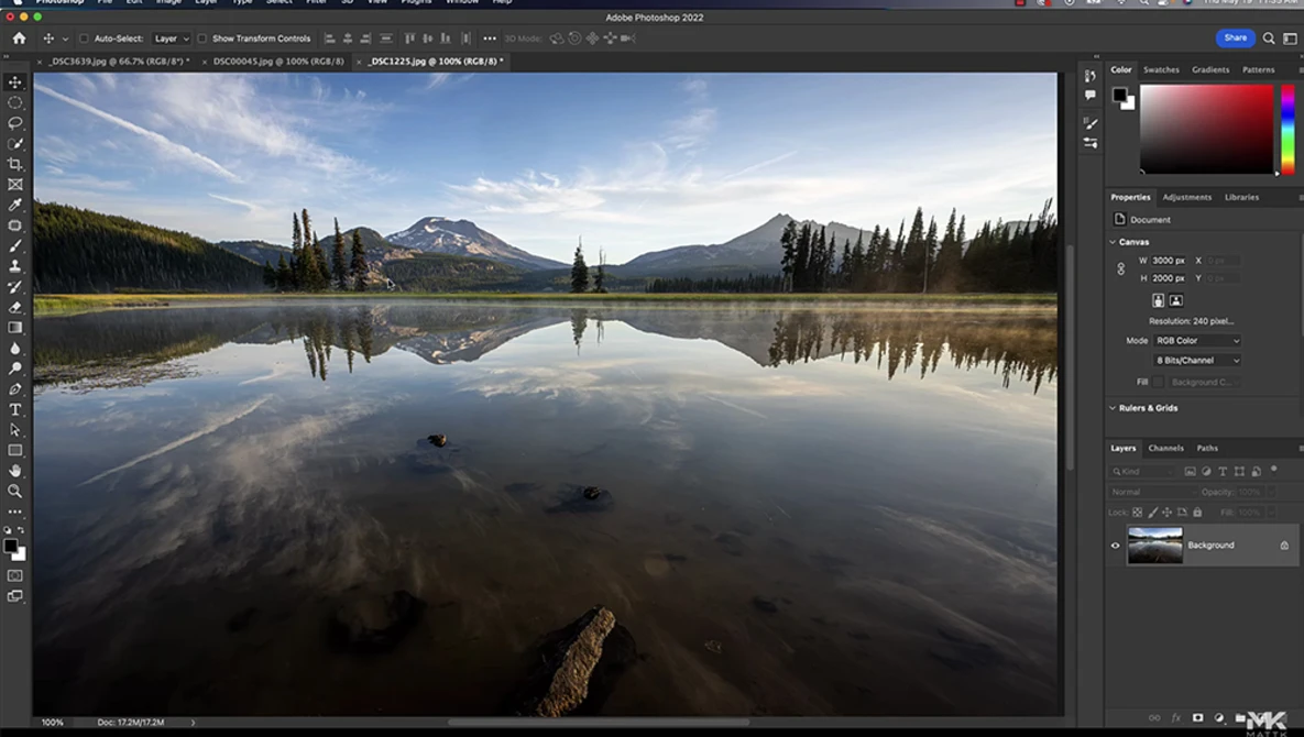 Mountain lake with perfect mirror reflection of snow-capped peaks and evergreen trees under clear sky.