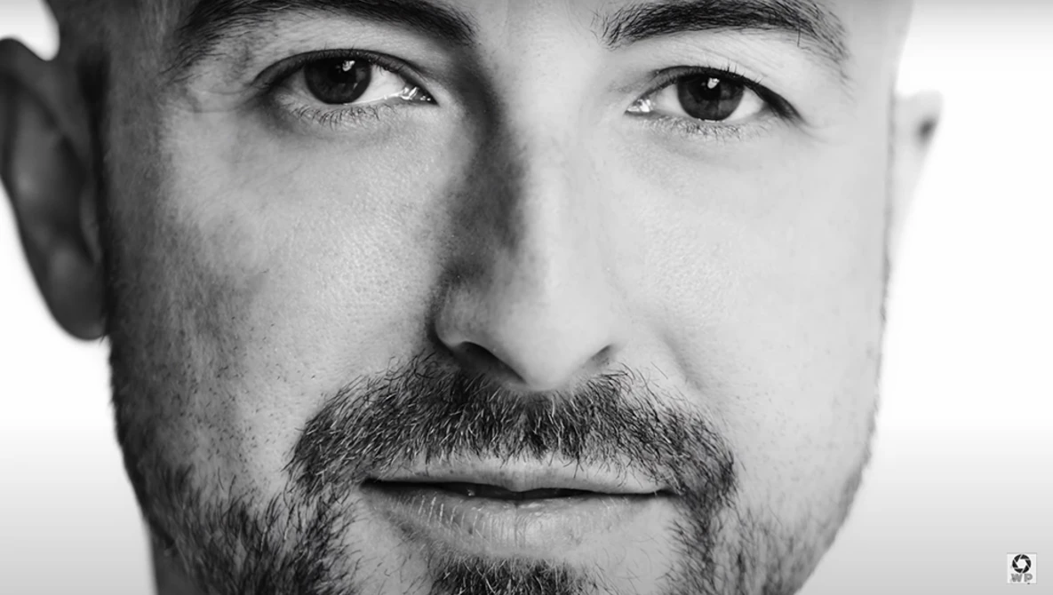 Black and white portrait of a man with dark eyes and full beard looking directly at camera.
