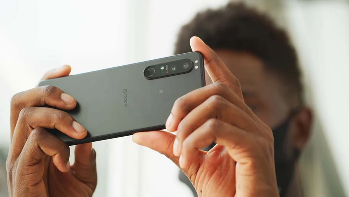 Person holding a Sony smartphone in landscape orientation while photographing, with camera module visible on the back.