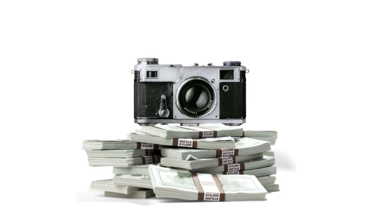 Vintage rangefinder camera positioned atop a stack of bundled currency bills.