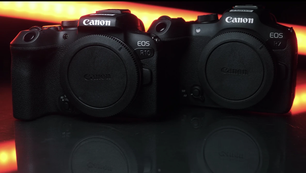 Two Canon EOS mirrorless camera bodies displayed side-by-side against a dramatic golden and orange gradient background.
