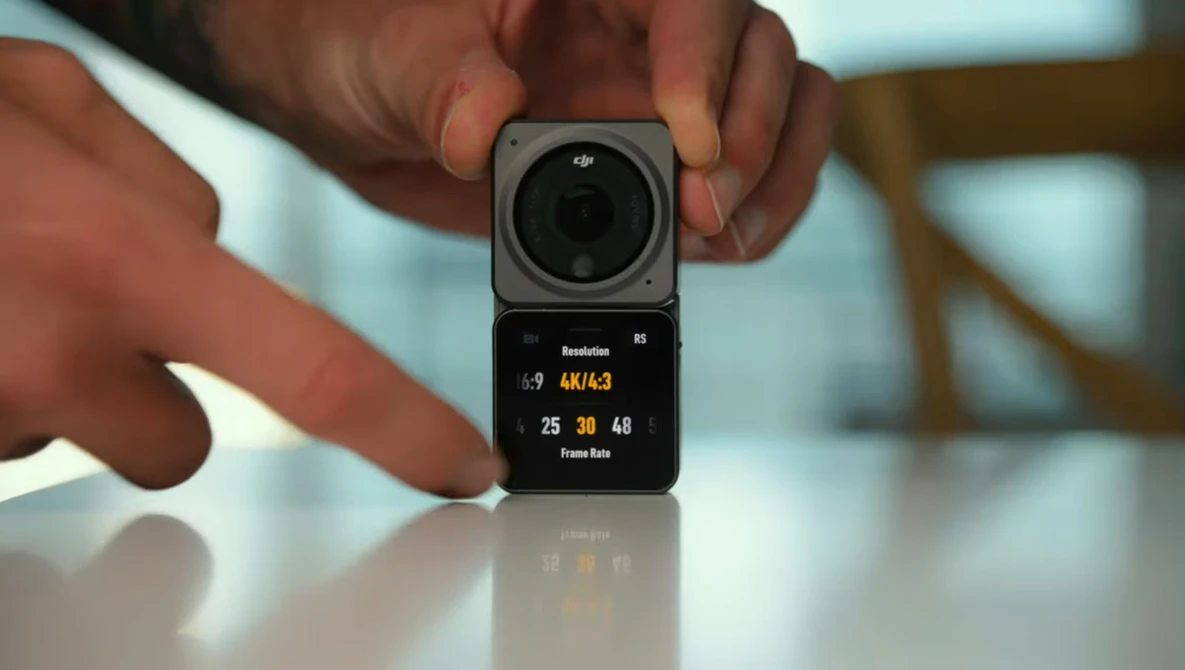 Compact modular camera system with square lens module mounted on rectangular display unit held in hands.