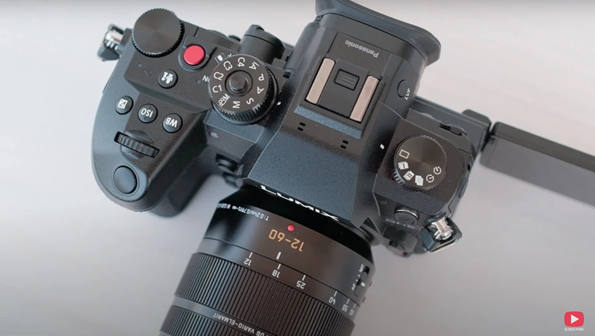 Professional cinema camera rig with wireless remote control and telephoto lens mounted on light gray surface.