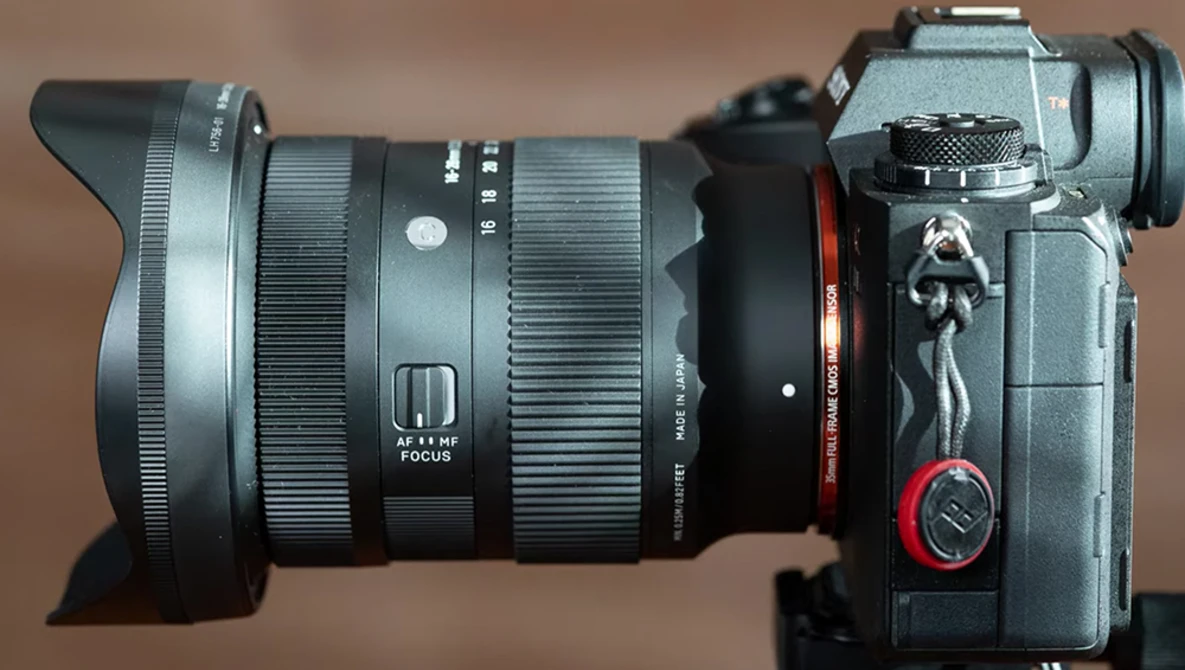 Wide-angle lens mounted on mirrorless camera body against neutral background.
