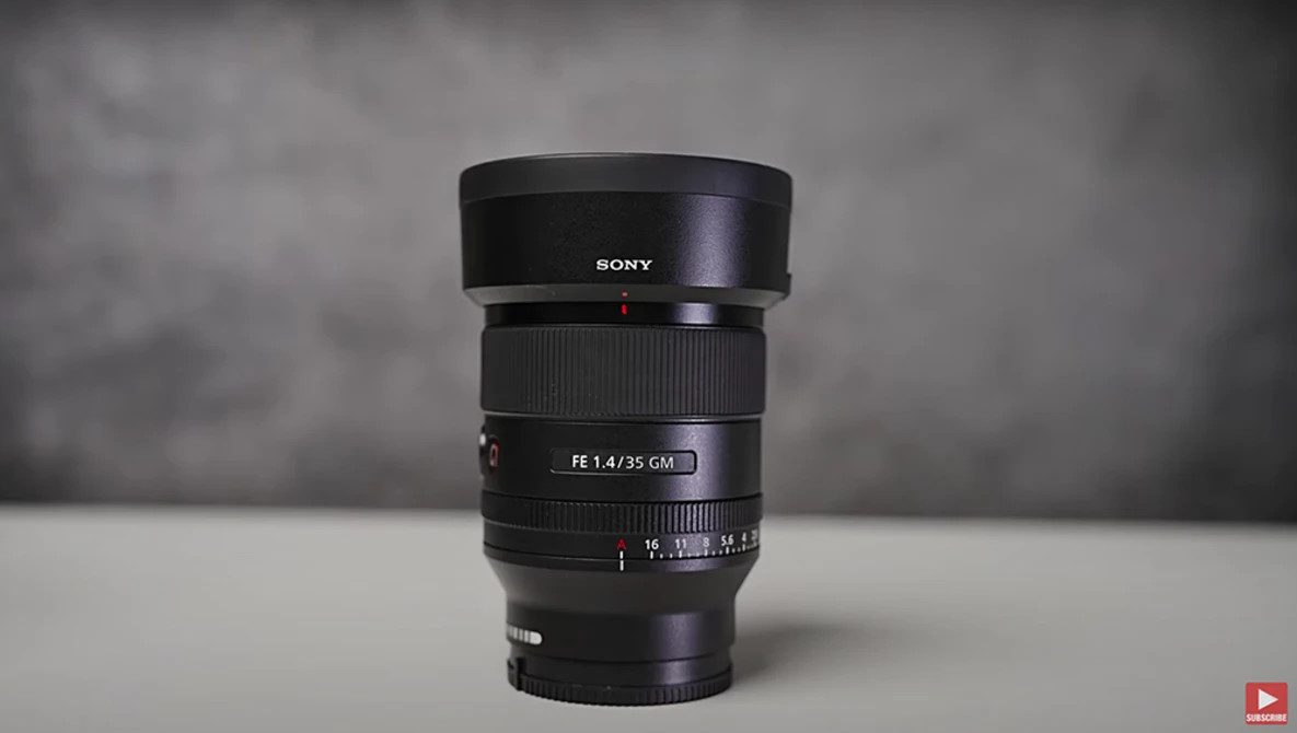 Sony FE 1.4/35 GM prime lens with hood mounted, displayed against neutral gray background.