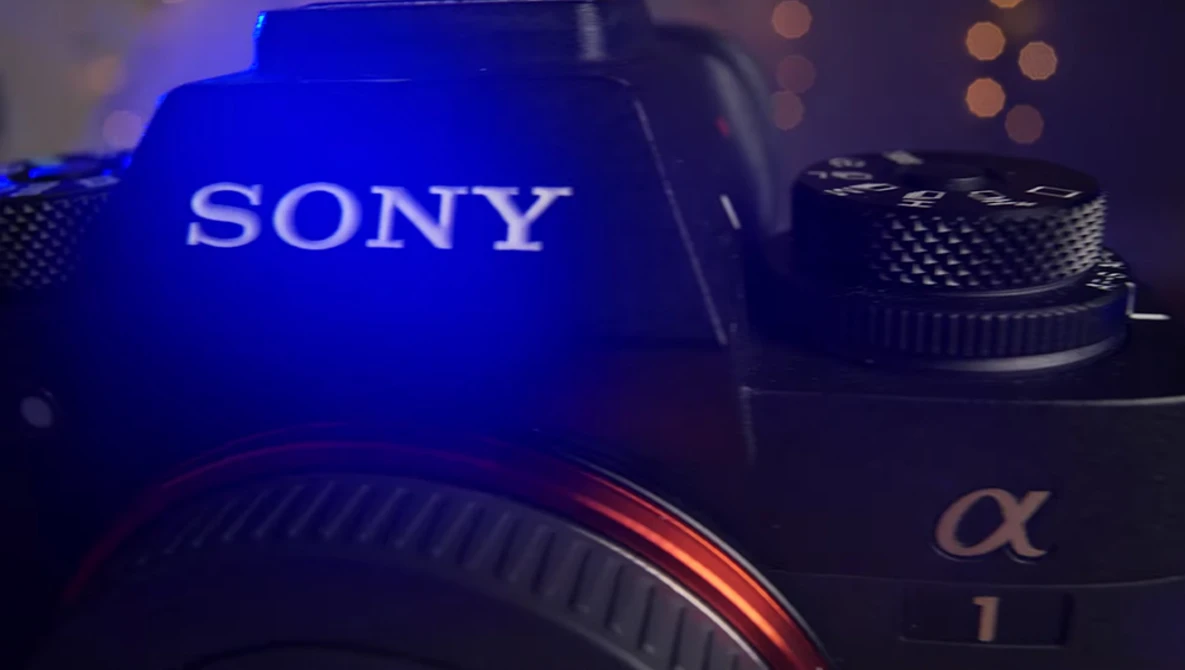 Sony alpha camera body illuminated by blue LED lighting with warm bokeh lights in background.