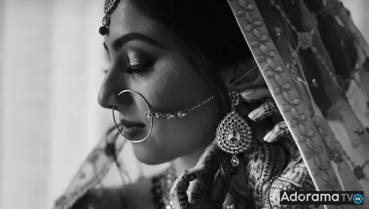 Woman in profile wearing traditional jewelry and ornate fabric, shot in black and white.