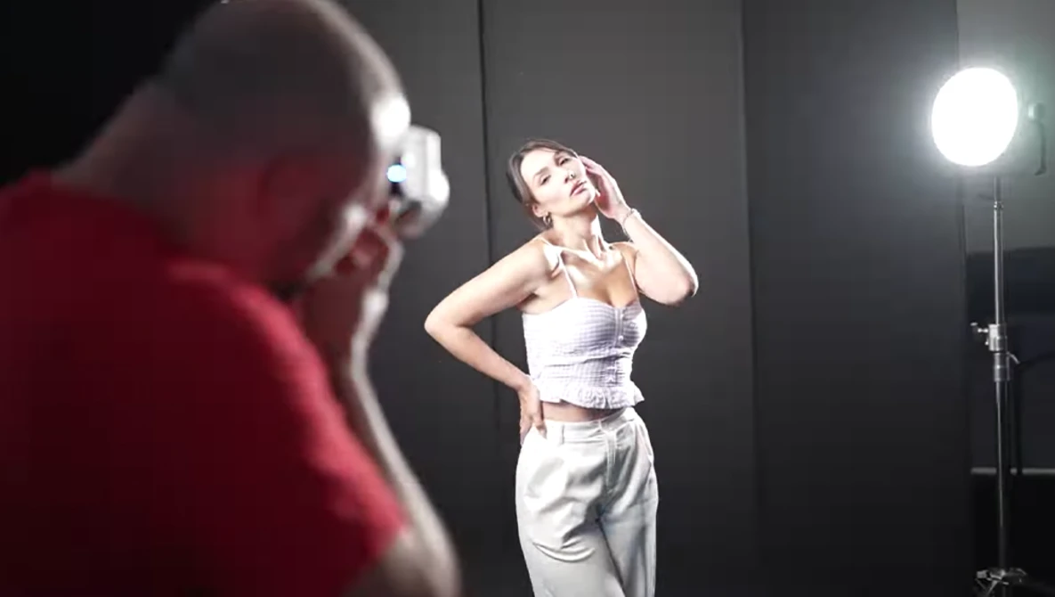 Female model posing during a studio photoshoot with professional lighting setup.
