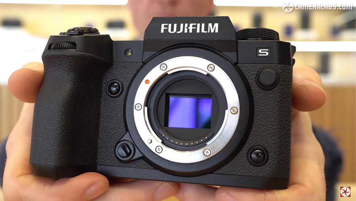 Fujifilm S5 mirrorless camera held in hands, showing open sensor mount with blue sensor visible.