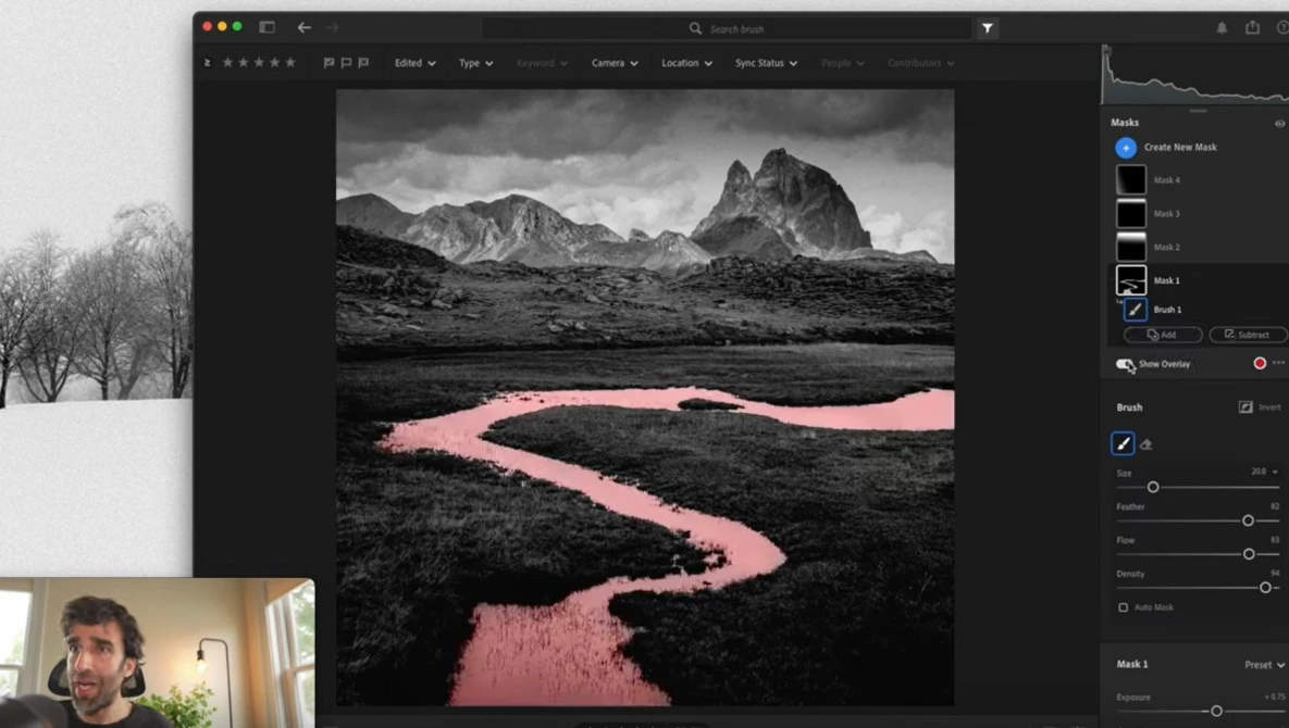Black and white landscape photograph with a pink-toned river winding through dark terrain toward jagged mountains under stormy skies.