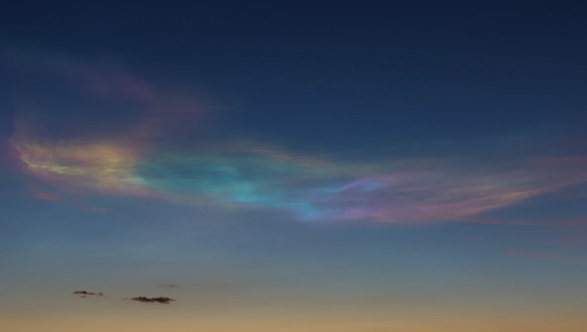 Twilight sky with iridescent cloud displaying rainbow-like colors against deepening blue.