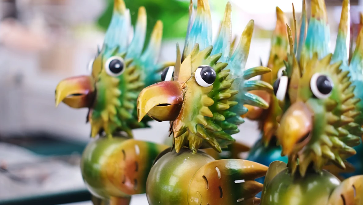 Colorful wooden bird figurines with green, blue, and yellow painted details and carved feather textures.