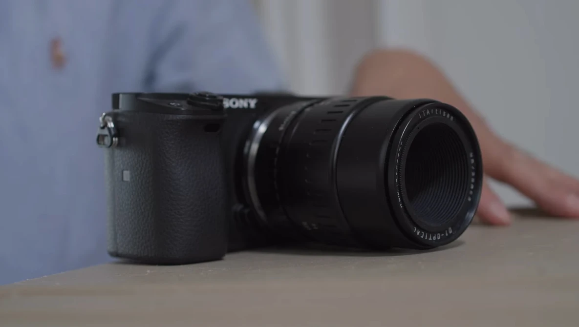 Sony mirrorless camera with attached telephoto lens on a table.