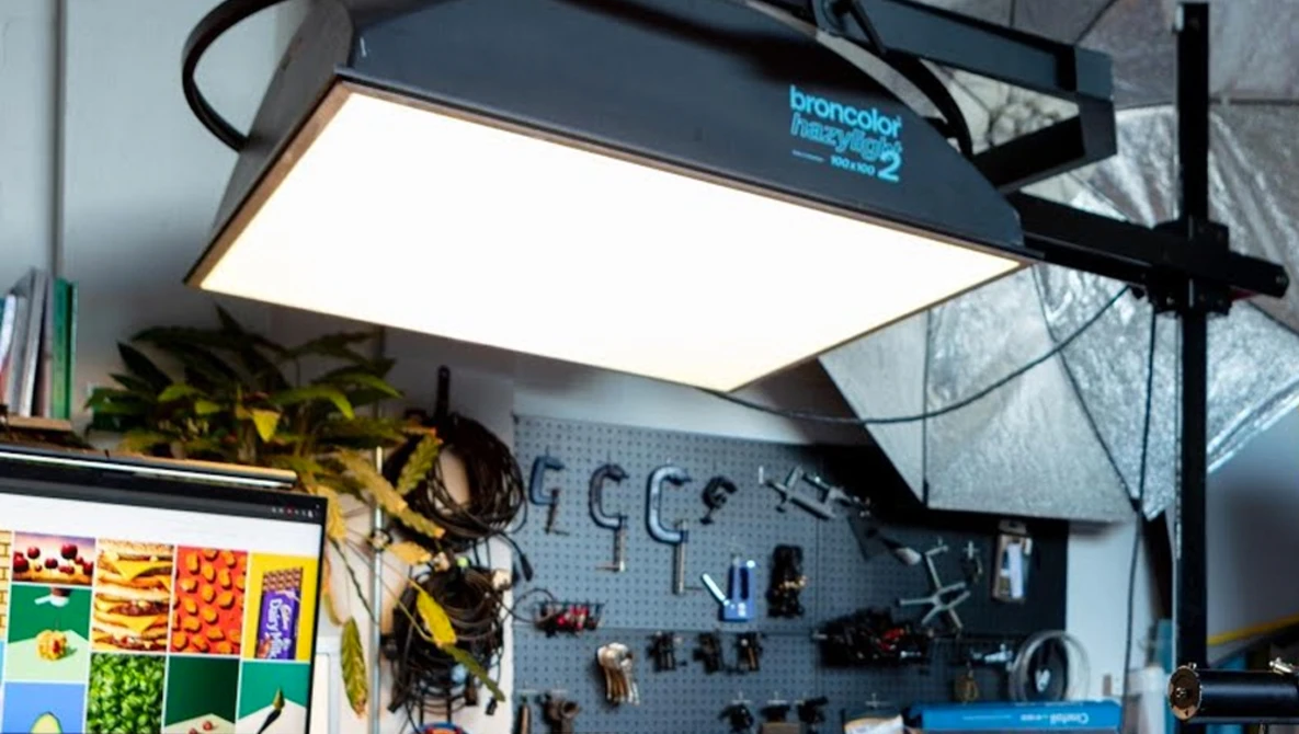 Professional studio workspace with overhead panel lighting and pegboard wall organization.
