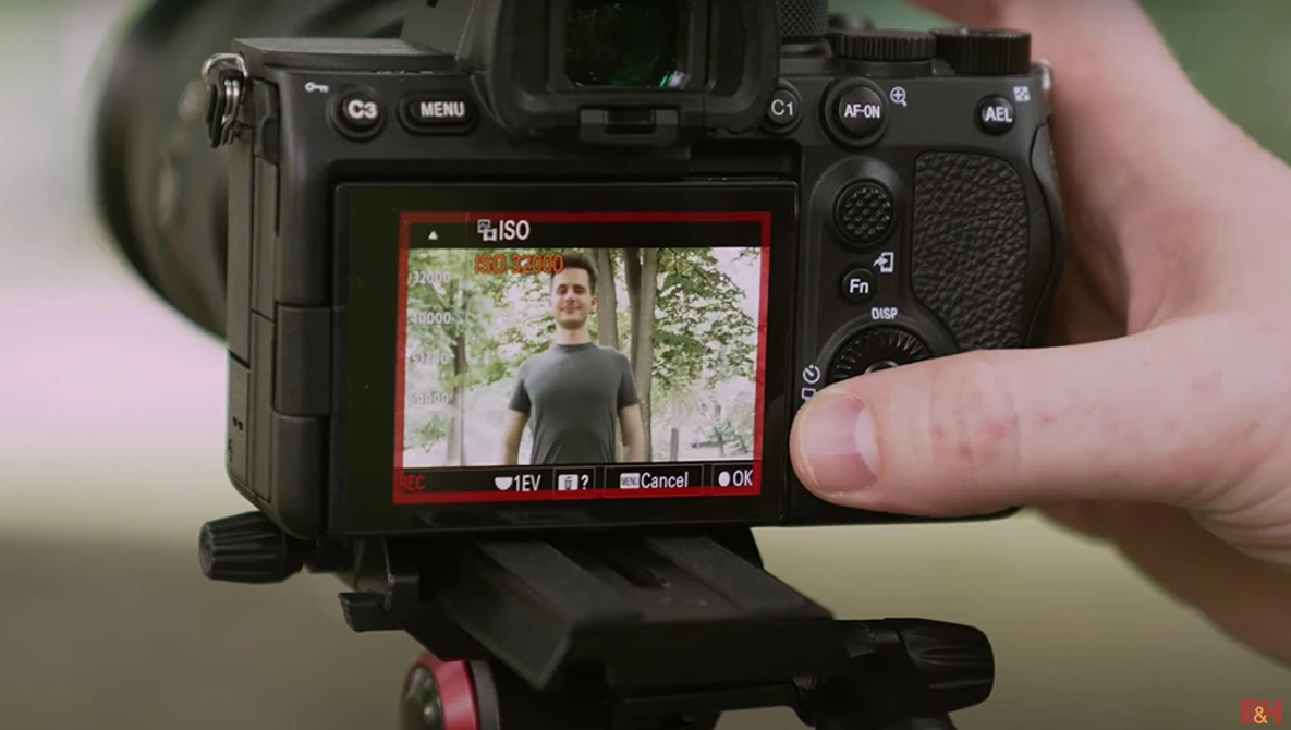 Camera LCD screen displaying a portrait of a man outdoors, with ISO and exposure controls visible.