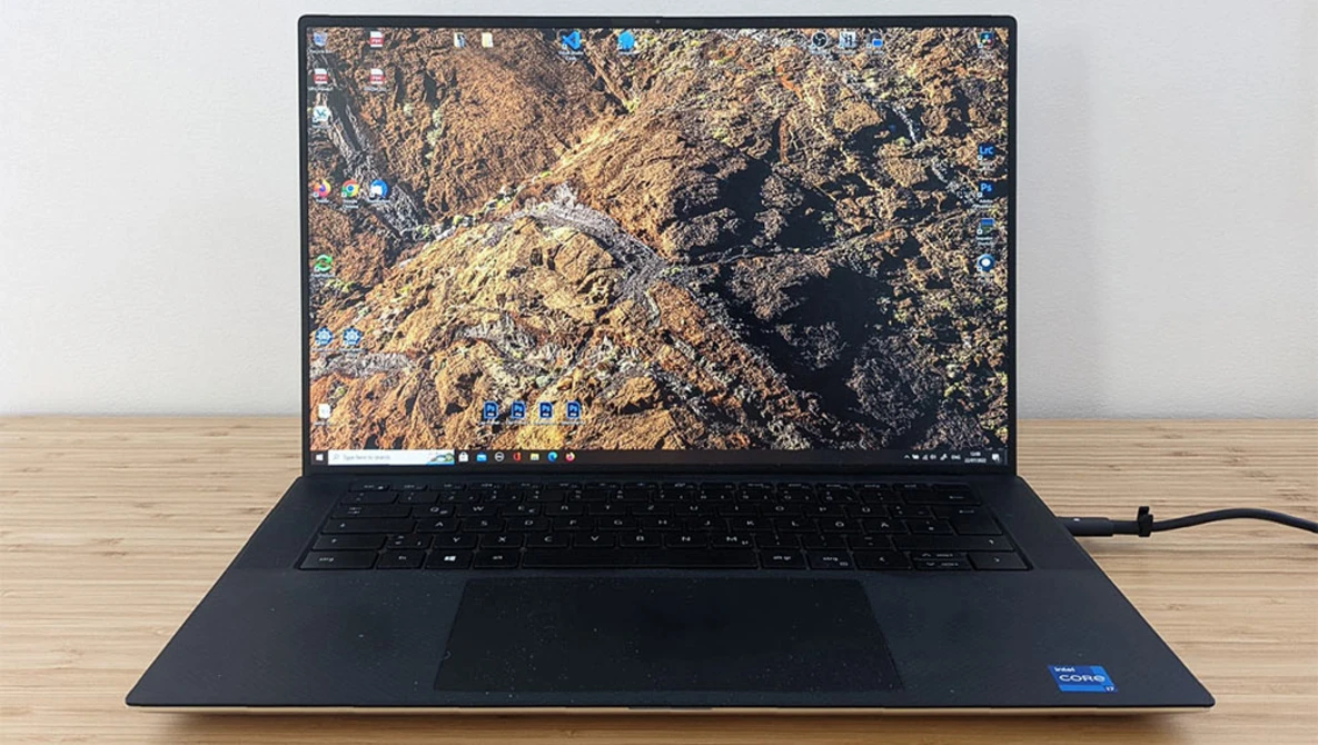 Dark laptop displaying aerial photograph of rocky, mountainous terrain with gold and blue tones.
