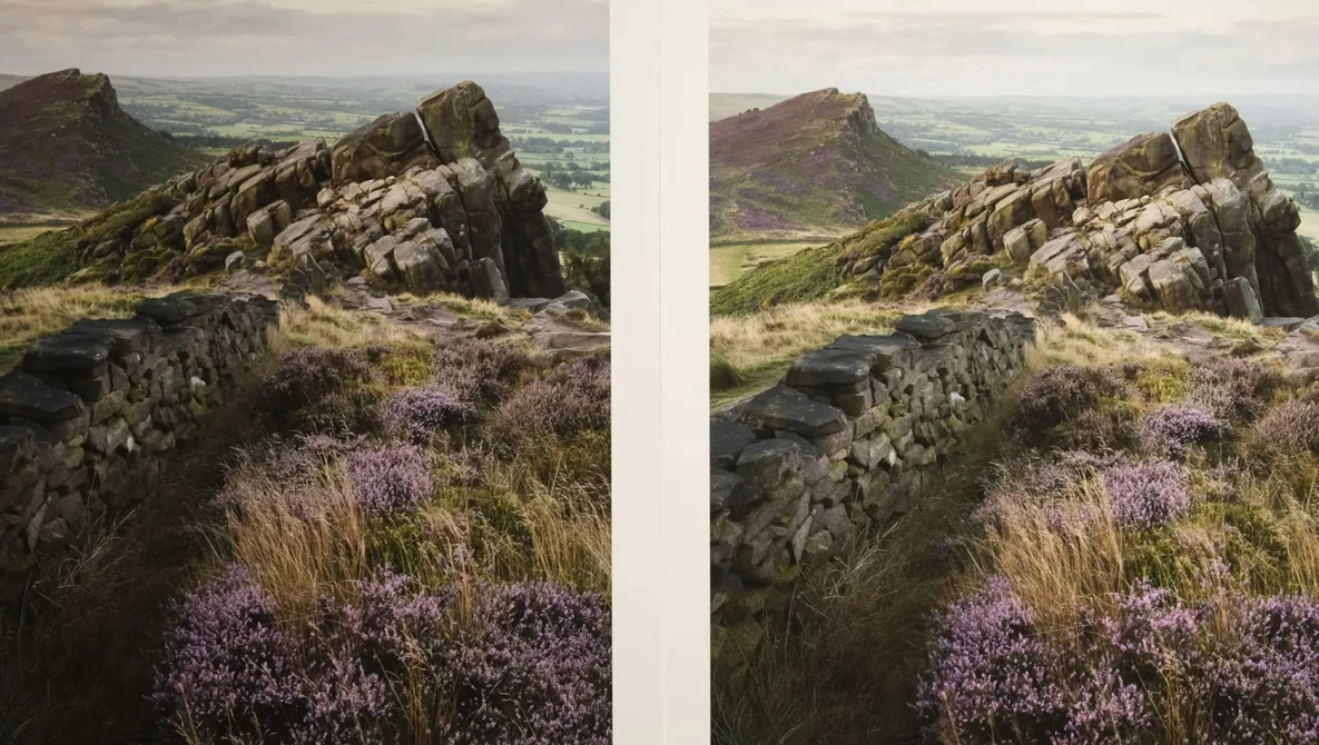 Rocky hilltop with purple heather and stone wall overlooking expansive valley landscape.