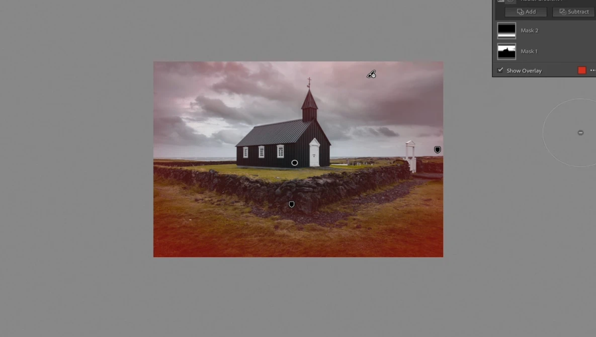 Isolated red-roofed church with white walls standing alone on russet terrain beneath dramatic clouded sky.