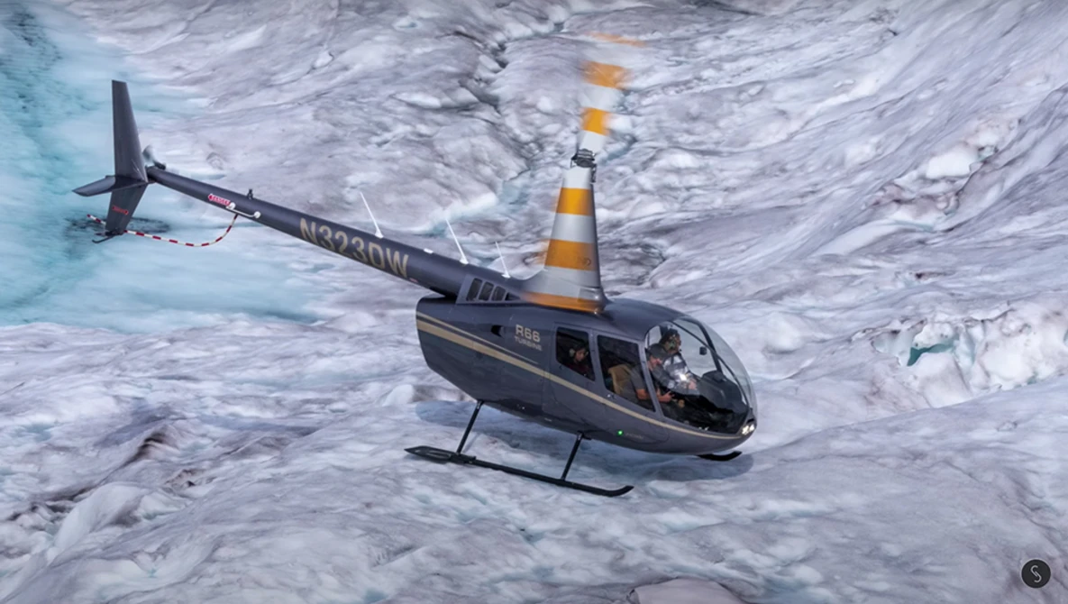 Black and orange helicopter hovering above glacial ice with turquoise meltwater visible at left.