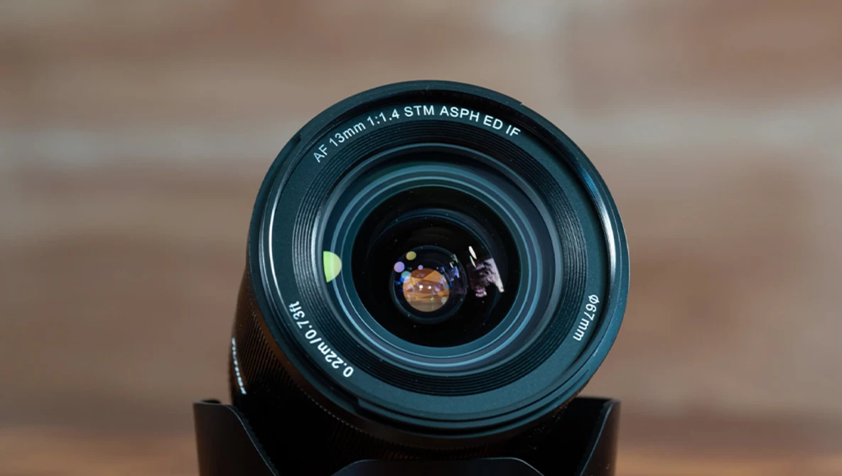 Canon 18-55mm f/3.5-5.6 STM lens viewed from front, showing glass elements and autofocus motor specifications.