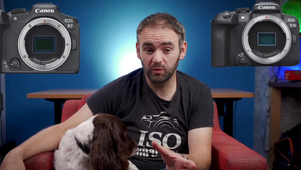 Man holding a brown and white dog, seated between two Canon EOS R mirrorless cameras displayed on a blue backdrop.