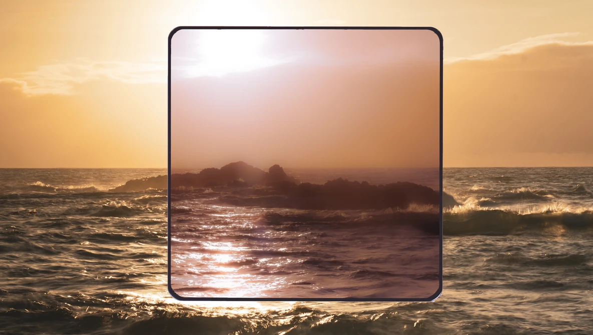 Golden hour seascape with a framed rectangular window revealing waves and rocky outcrops at sunset.