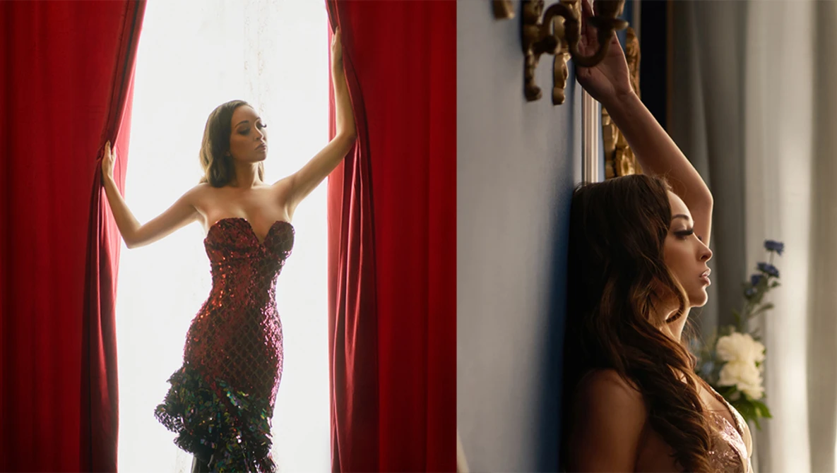 Woman in burgundy sequined dress opening red velvet curtains beside a mirror reflection.