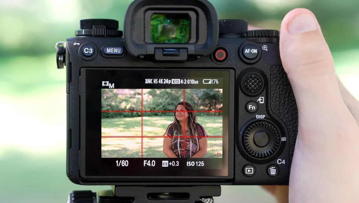Screenshot showing camera LCD display with live view of woman in red shirt, exposure settings visible at bottom.