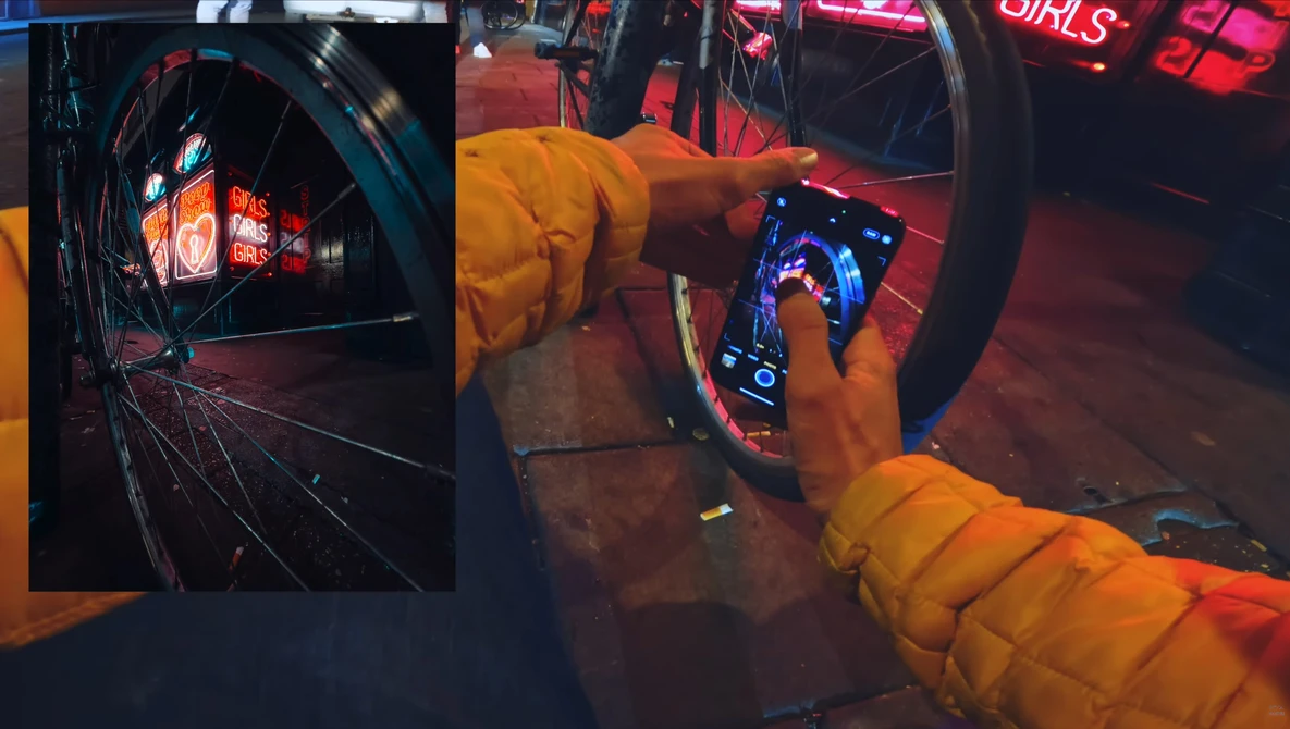 Hands in yellow jacket operating illuminated arcade game controls at night.