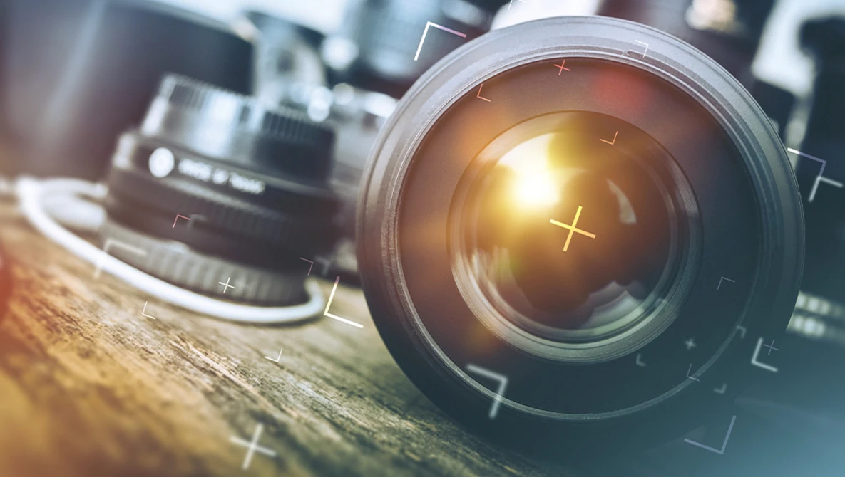 Close-up of a camera lens with bright golden light reflecting through the glass elements.