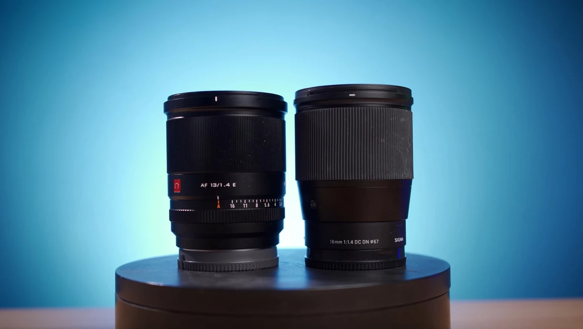 Two camera lenses displayed side by side on a cylindrical platform against a blue gradient background.