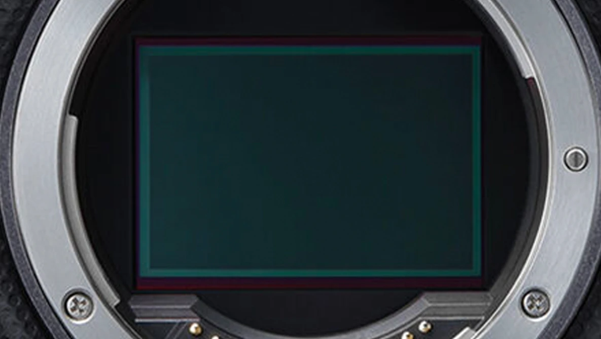 Close-up of a camera's mirror box interior showing the exposed sensor with a green-tinted protective frame.