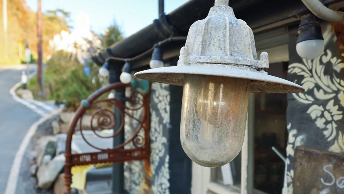 Weathered vintage-style wall sconce with frosted glass cylinder and metal cap mounted on an ornate bracket.