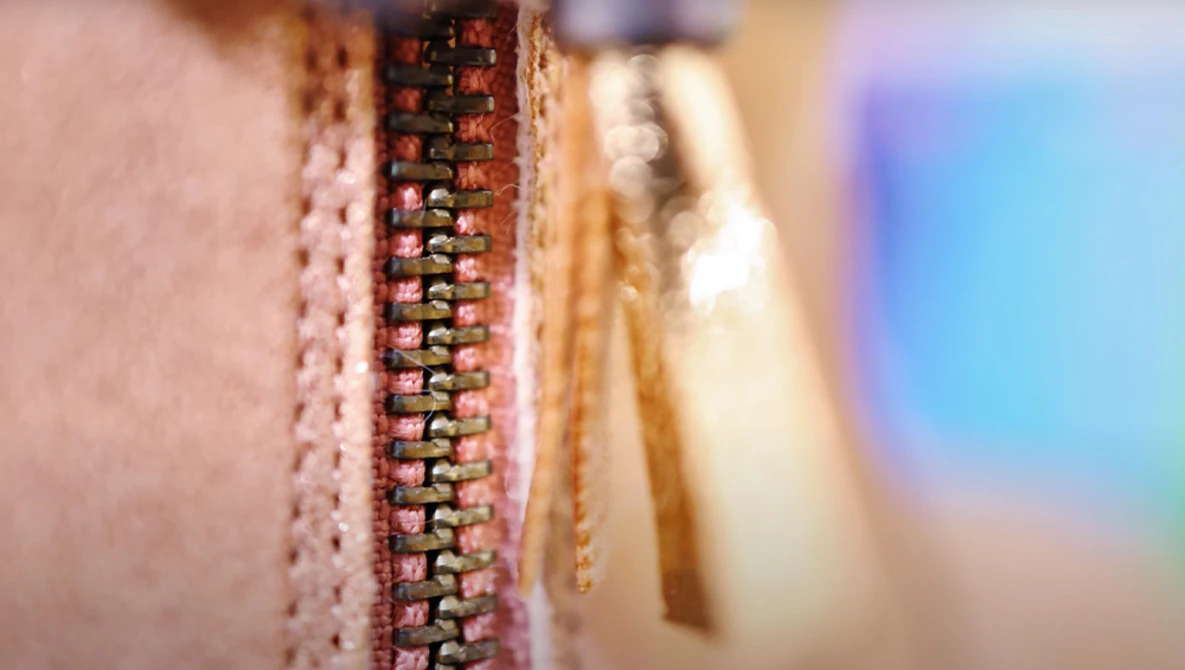 Close-up macro photograph of a zipper pull and metal teeth with shallow depth of field.