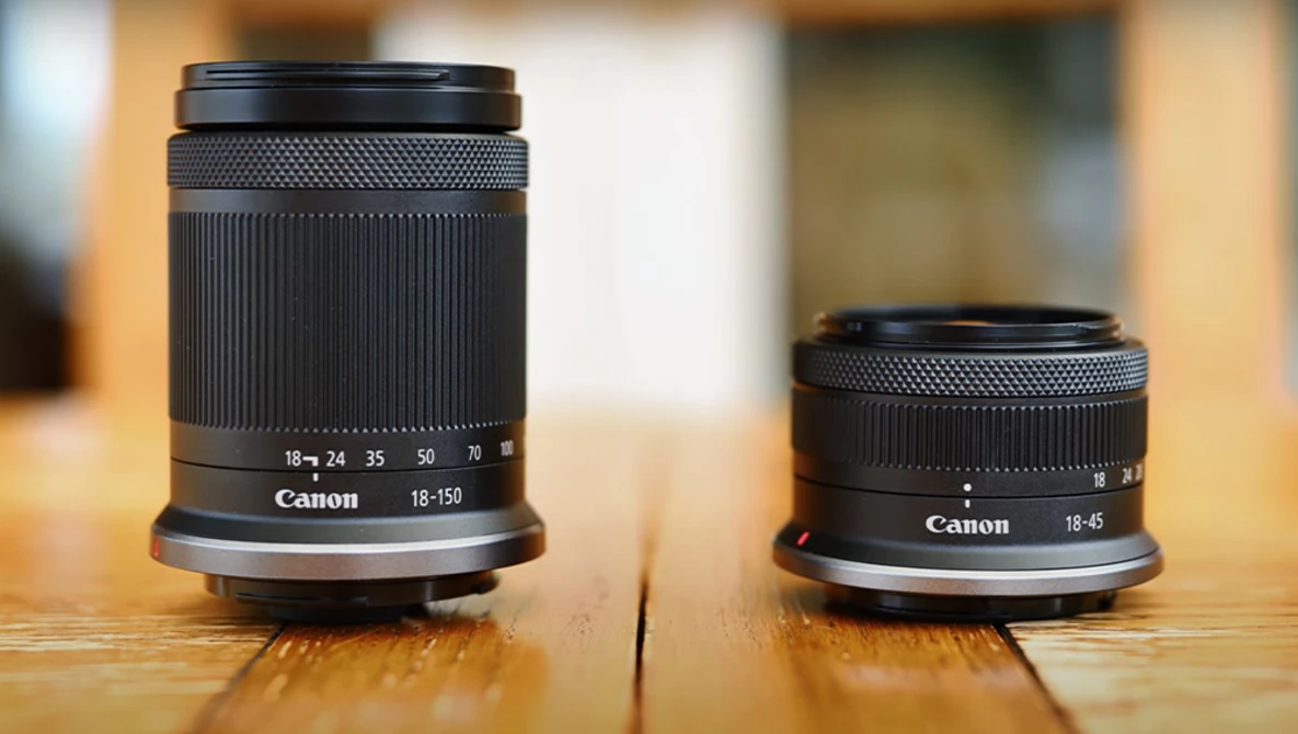 Canon 18-135mm and 18-45mm lenses side by side on wooden surface.
