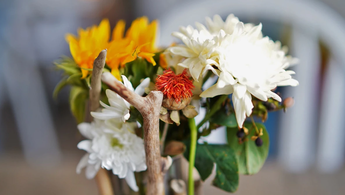 Mixed bouquet of white dahlias, yellow and red flowers with green stems in soft focus.