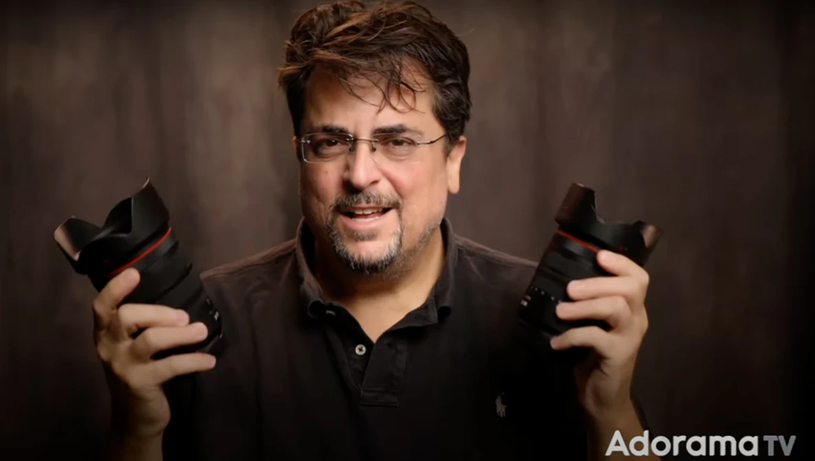 Man holding two video game controllers against a neutral backdrop.