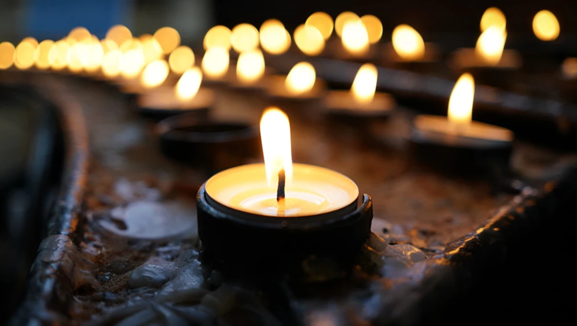 Tea light candles arranged on a textured surface with selective focus on the nearest flame.