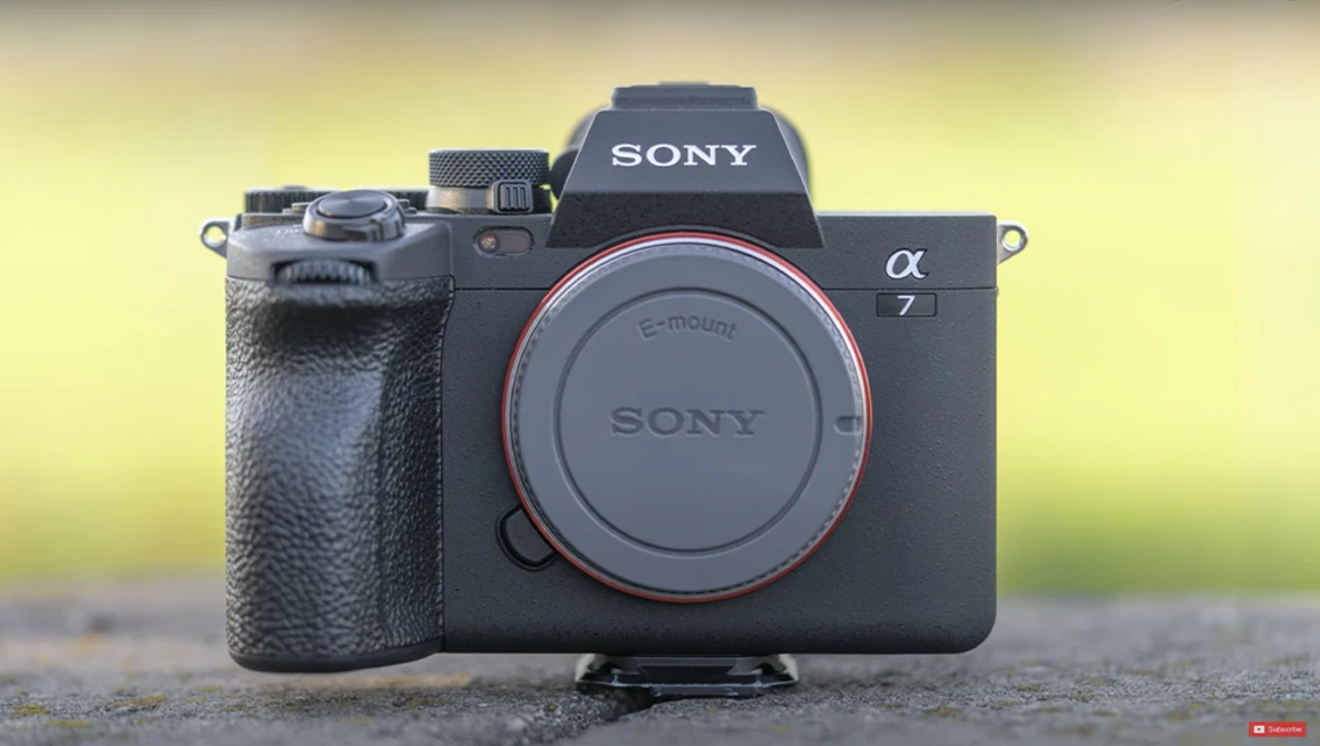 Sony a7 mirrorless camera body with attached grip, displayed against blurred yellow-green background.
