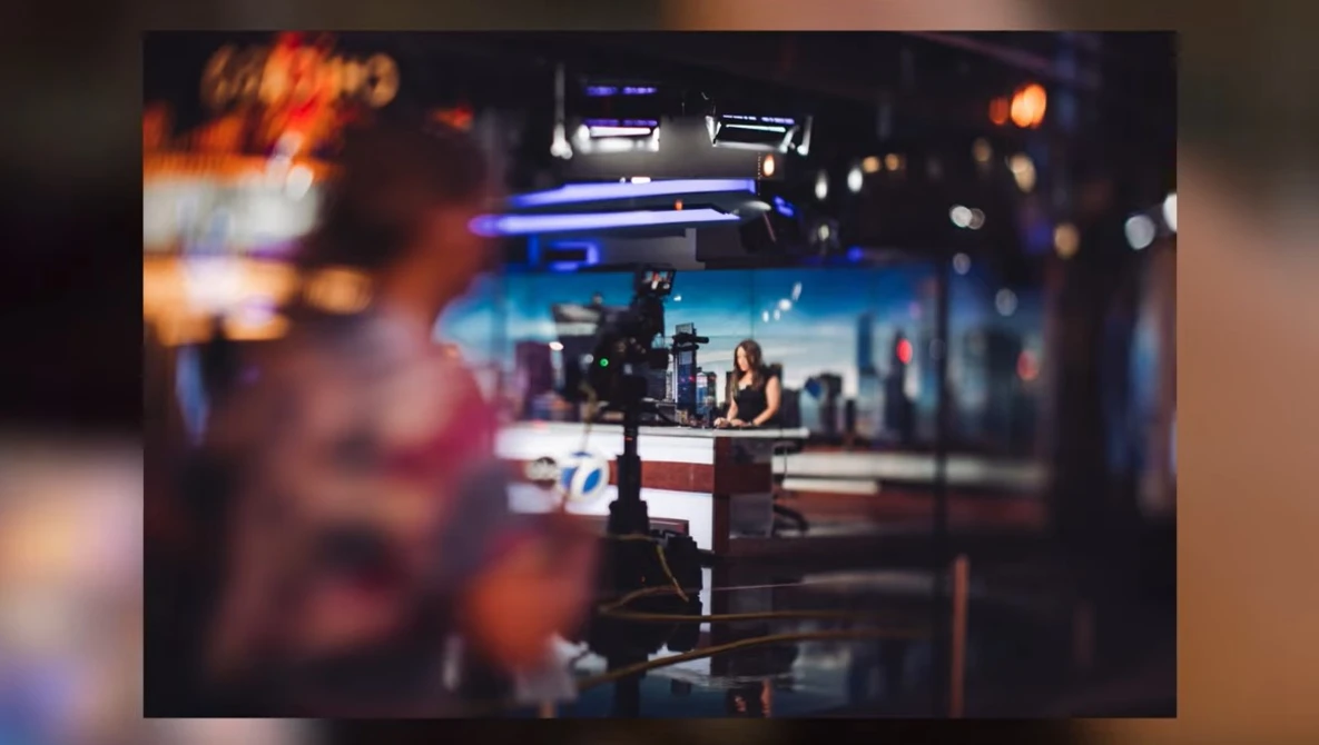Television studio set with news desk, camera, and studio lighting during a broadcast production.